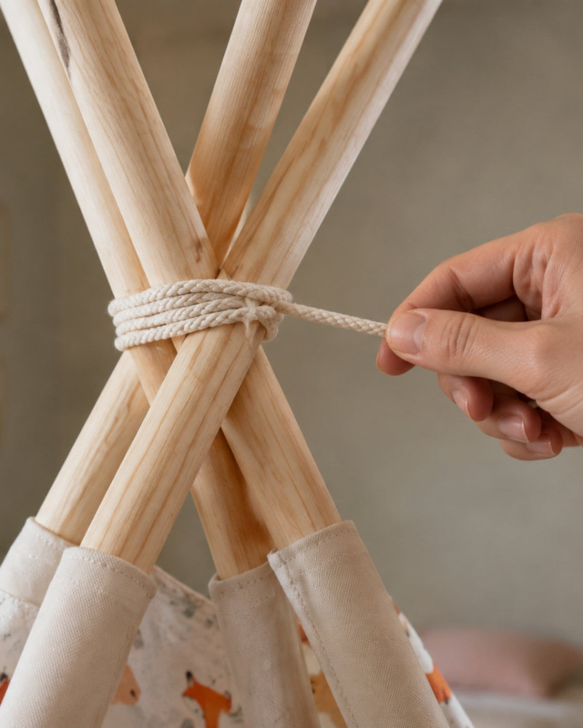 Hand tying the cord at the top of the pine poles