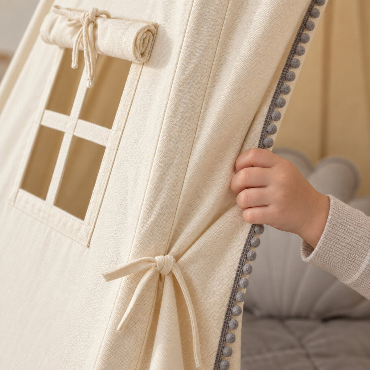 Close-up of the grey pompom trim on cream cotton canvas